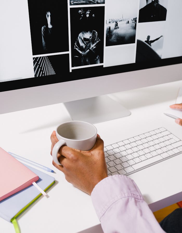 Crop anonymous African American female using computer and mouse while working at white table in daylight